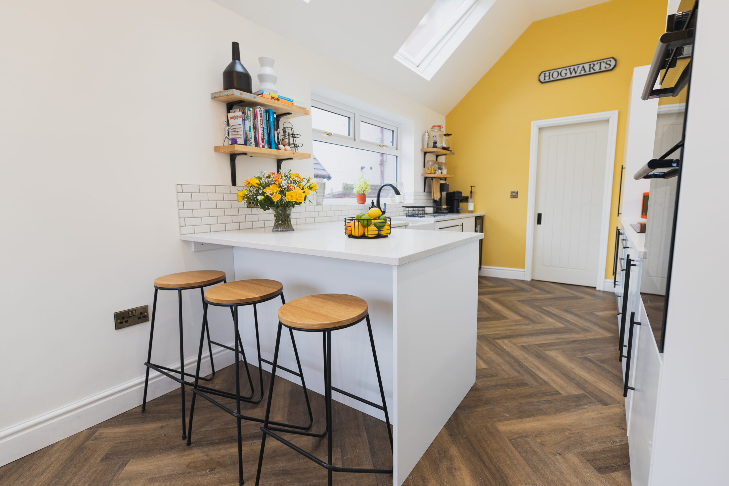 Ice White Quartz breakfast bar island with bar stools in a bright kitchen, showing a smooth white surface finish