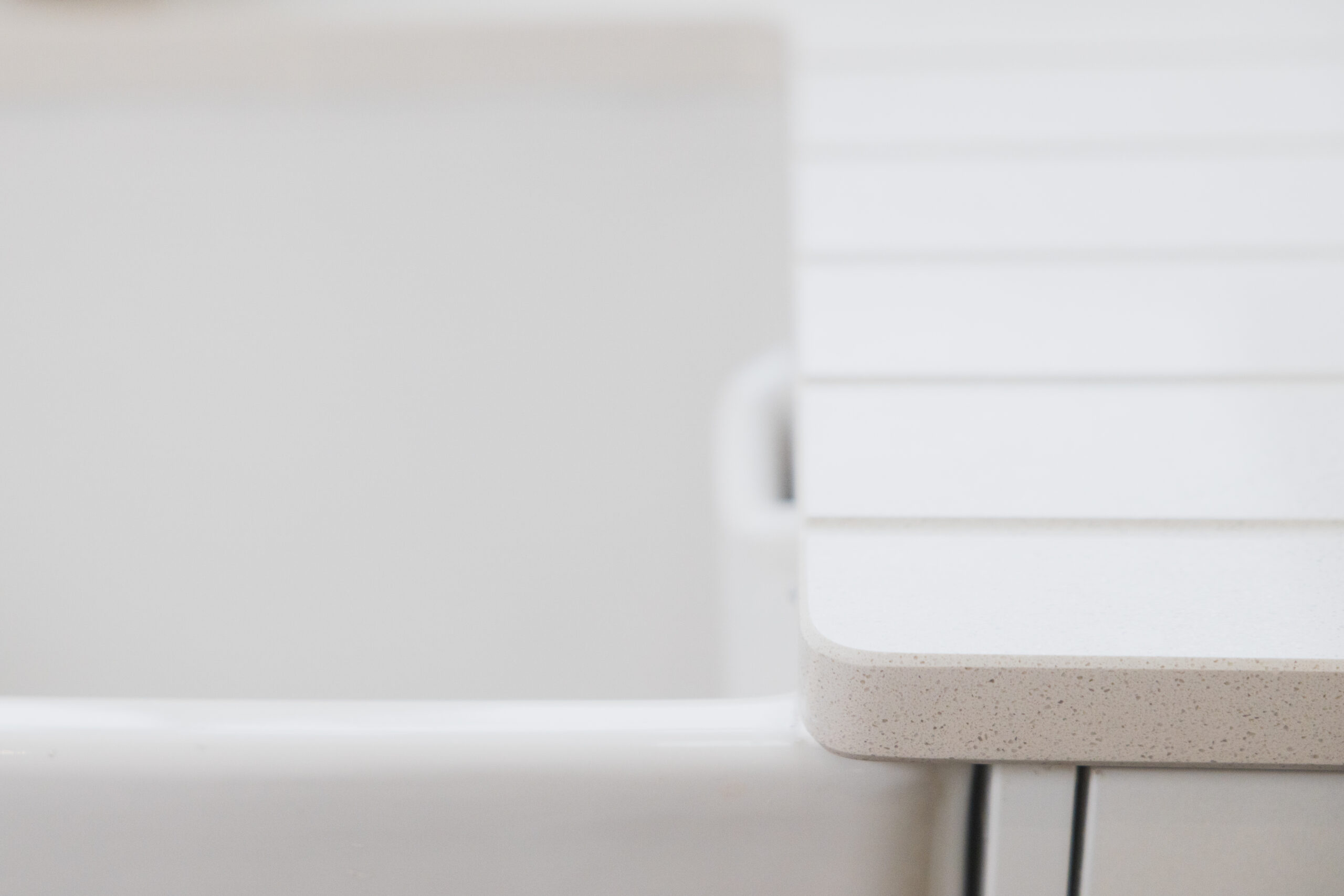 Close-up of Ice White Quartz worktop edge beside a sink, showing a smooth rounded corner and bright finish