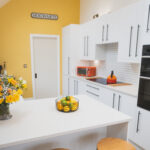 Ice White Quartz island worktop with a smooth white finish in a bright kitchen with white cabinets