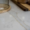 Close up of Gold Calacatta worktop surface showing warm veining beneath glassware