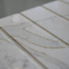 Gold Calacatta worktop with warm veining and precision cut drainer grooves