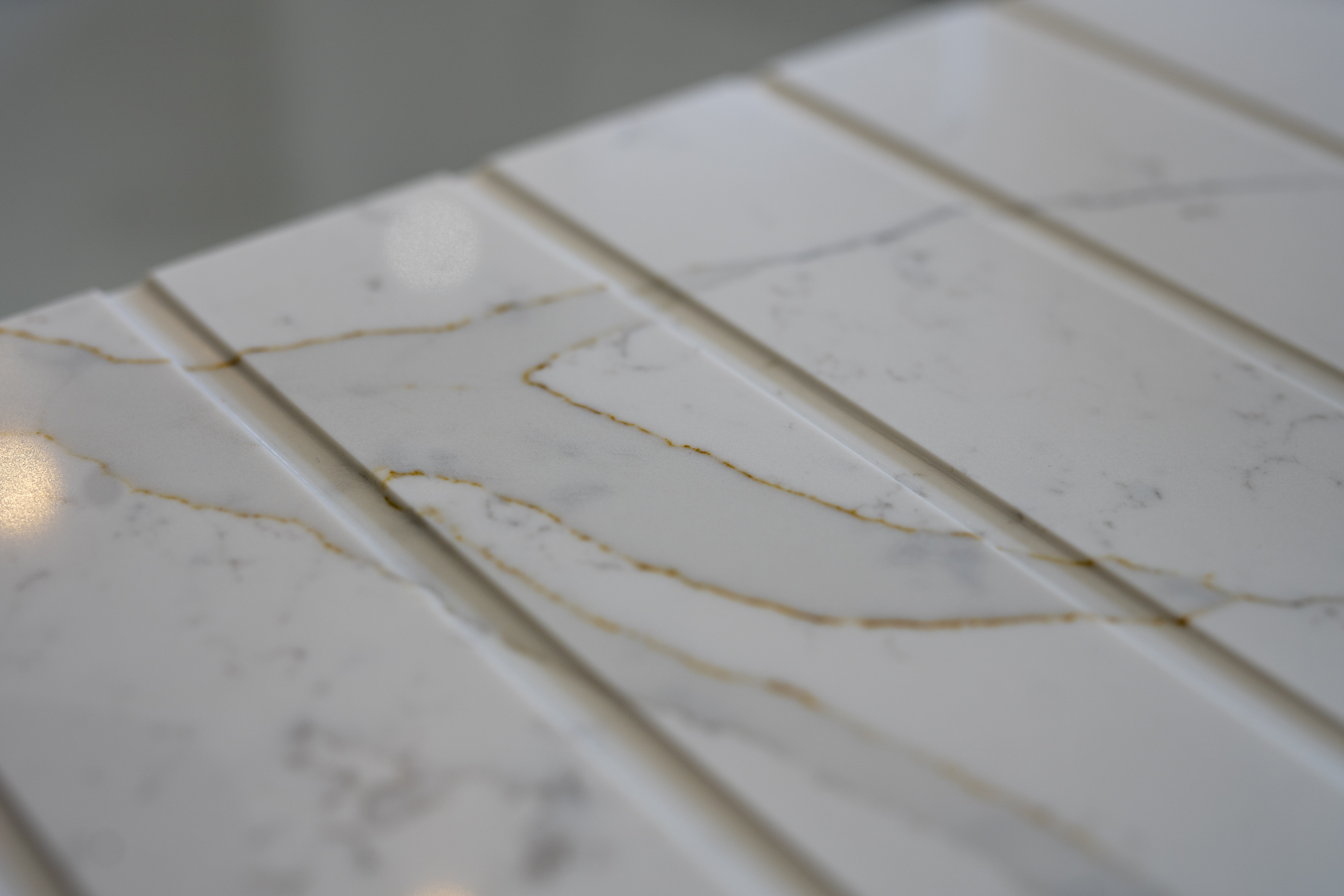 Gold Calacatta worktop with warm veining and precision cut drainer grooves