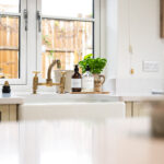 Wide kitchen view with Ice White Quartz worktops around the sink area, brass tap and drainer grooves visible