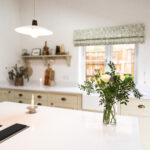 Ice White Quartz island worktop in a bright kitchen with a smooth white finish and fresh flowers on the surface