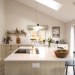 Long view of a kitchen island with Ice White Quartz worktop and integrated hob, showing a smooth bright surface