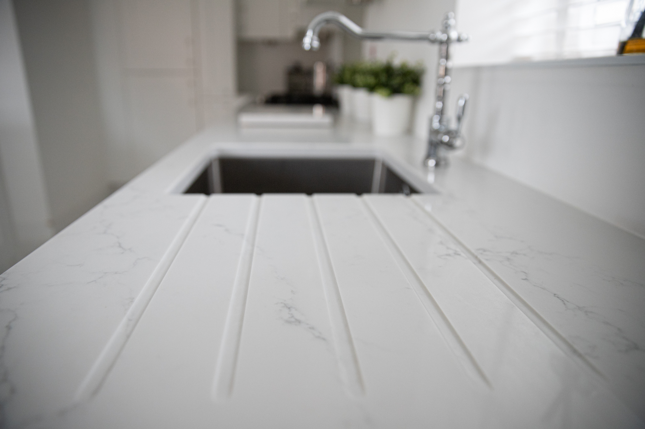 Statuario Bianco Porcelain drainer grooves beside sink showing subtle grey veining
