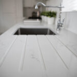 Statuario Bianco Porcelain drainer grooves beside sink showing subtle grey veining