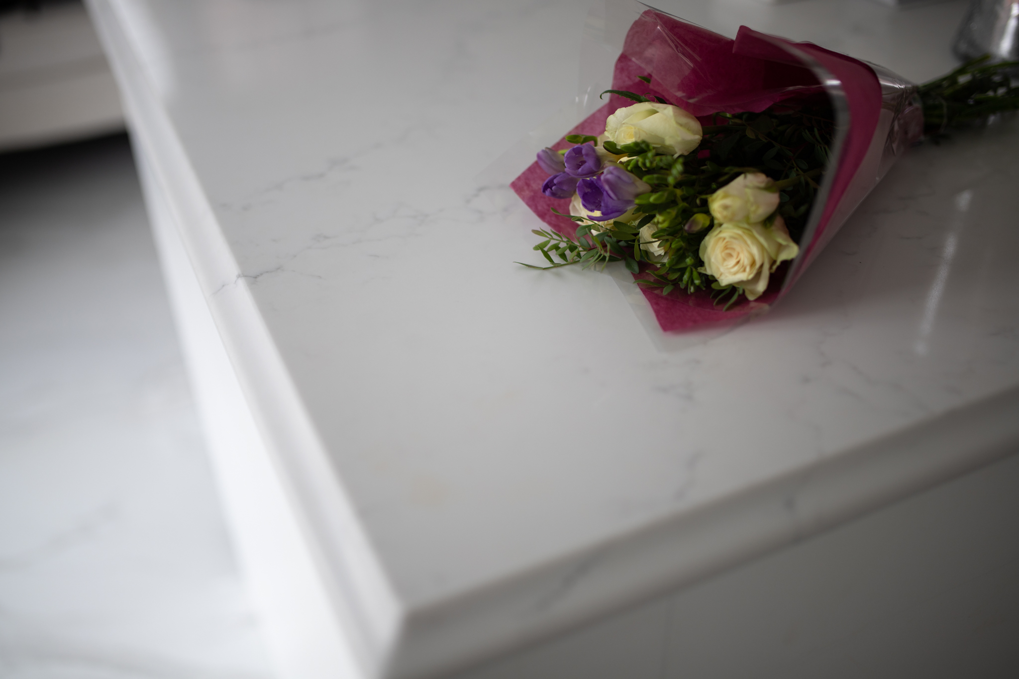 Statuario Bianco Porcelain worktop edge with subtle veining and flowers styled on the surface