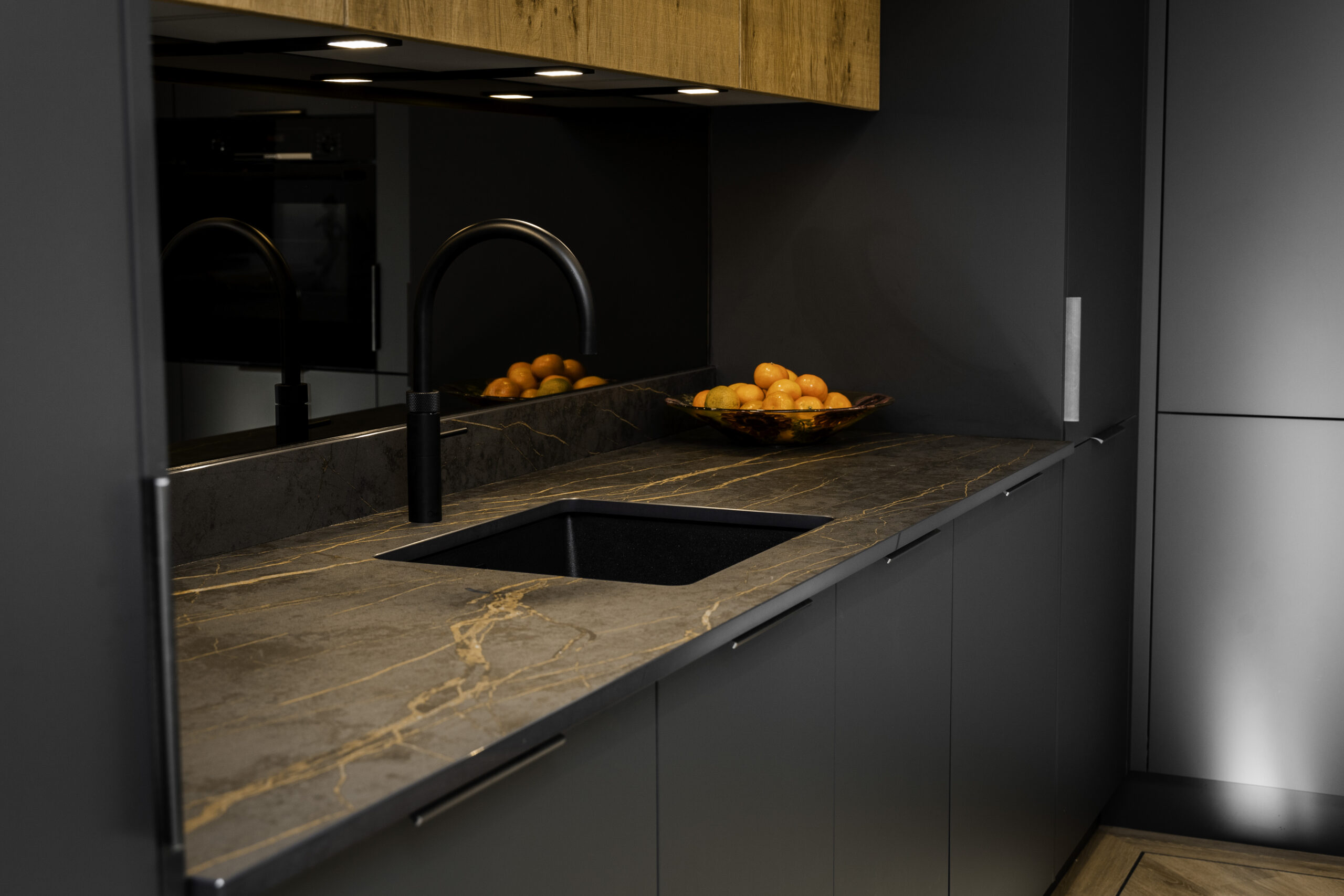 Laurent Porcelain worktop with gold veining featuring a flush black induction hob and matching upstand in a dark kitchen.