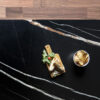 Noir St Laurent Porcelain worktop slab close up showing deep black surface with bold gold veining, styled with food and accessories