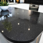 Black Starlight Quartz island worktop close-up showing sparkle flecks and a rounded corner profile