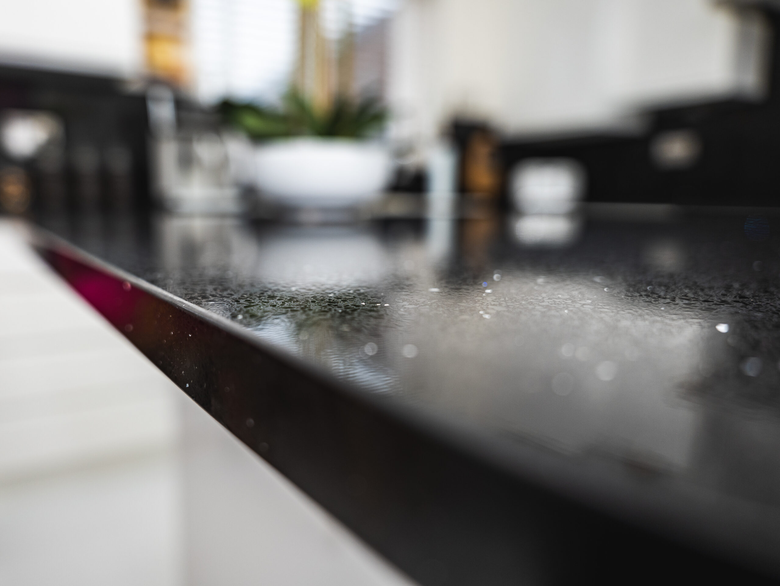 Macro close-up of Black Starlight Quartz worktop showing fine reflective speckles on a polished black surface