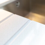 Ice White Quartz drainer grooves close-up beside an inset sink in a narrow boat kitchen