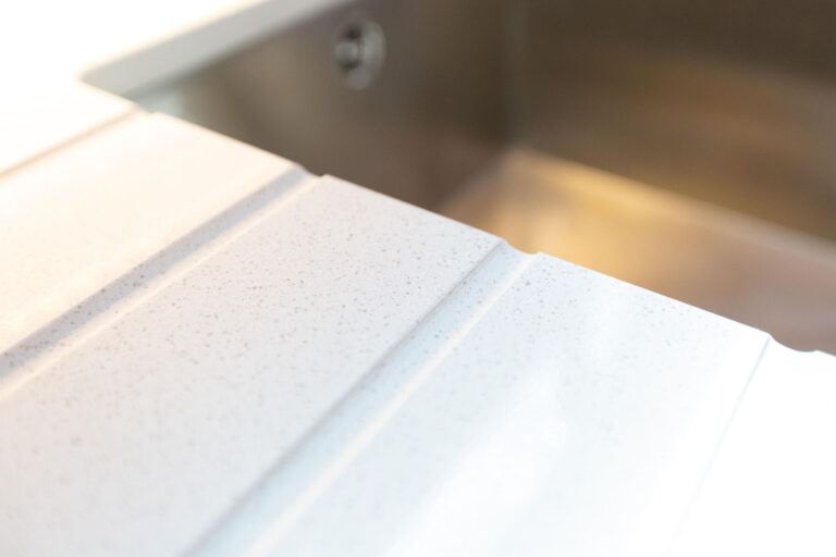 Ice White Quartz drainer grooves close-up beside an inset sink in a narrow boat kitchen