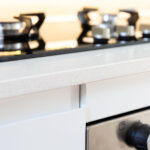 Close-up of a gas hob set into an Ice White Quartz worktop with the front edge and drawer details visible