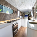 Wide view down a narrow boat galley with Ice White Quartz worktops and a hob set into the main run