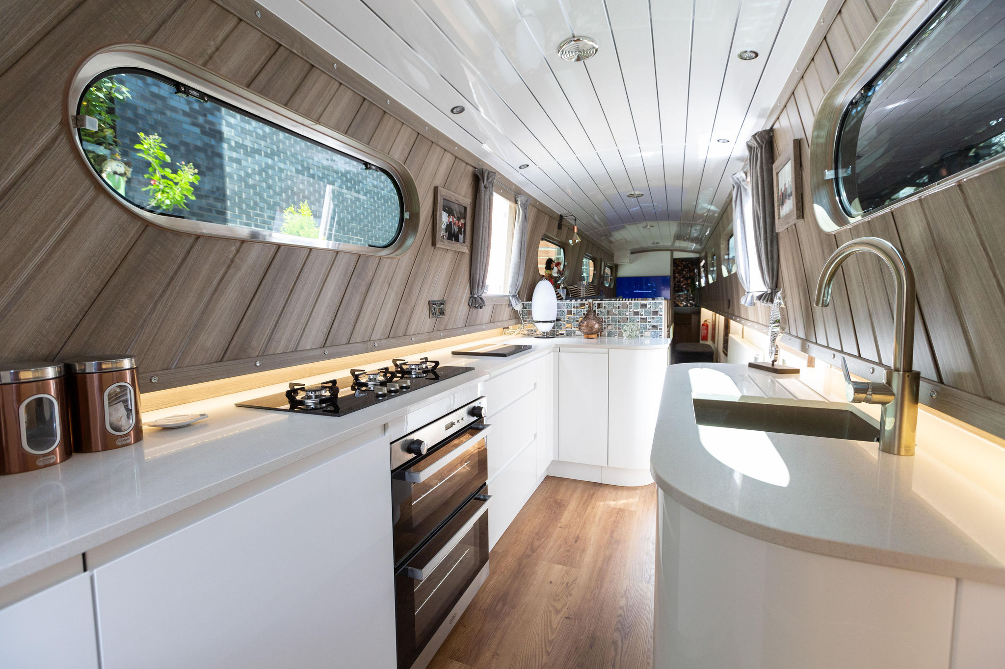 Wide view down a narrow boat galley with Ice White Quartz worktops and a hob set into the main run