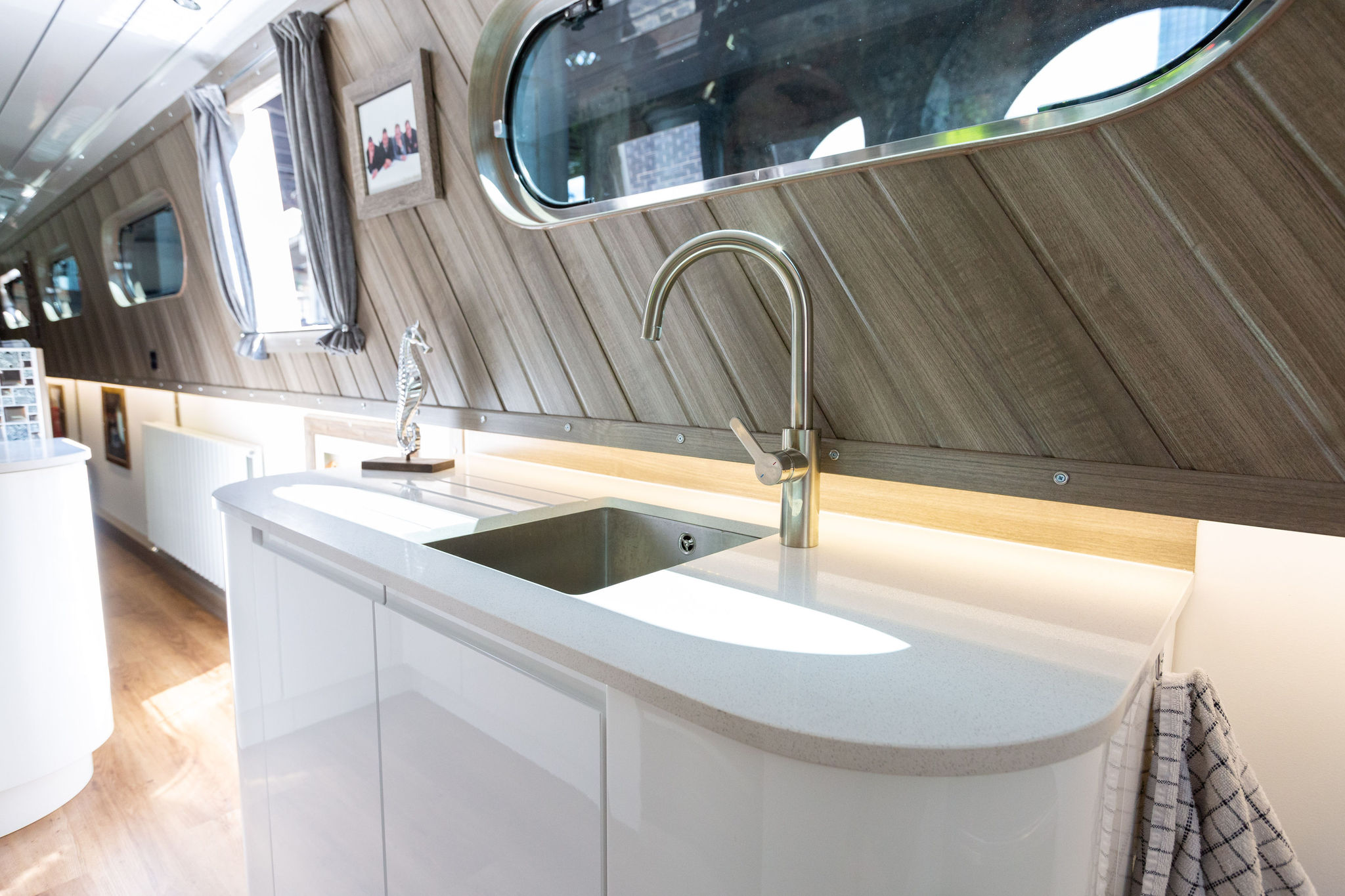 Sink and tap area in a narrow boat kitchen with Ice White Quartz worktop and curved end section