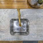 Top down sink detail in Ivory Fantasy Granite with a brass tap, highlighting the Granite veining and smooth polished surface around the sink.