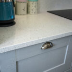 White Starlight Quartz worktop corner above grey cabinetry with modern hardware