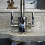 Chrome tap fitted on White Starlight Quartz worktops beside a stainless steel sink