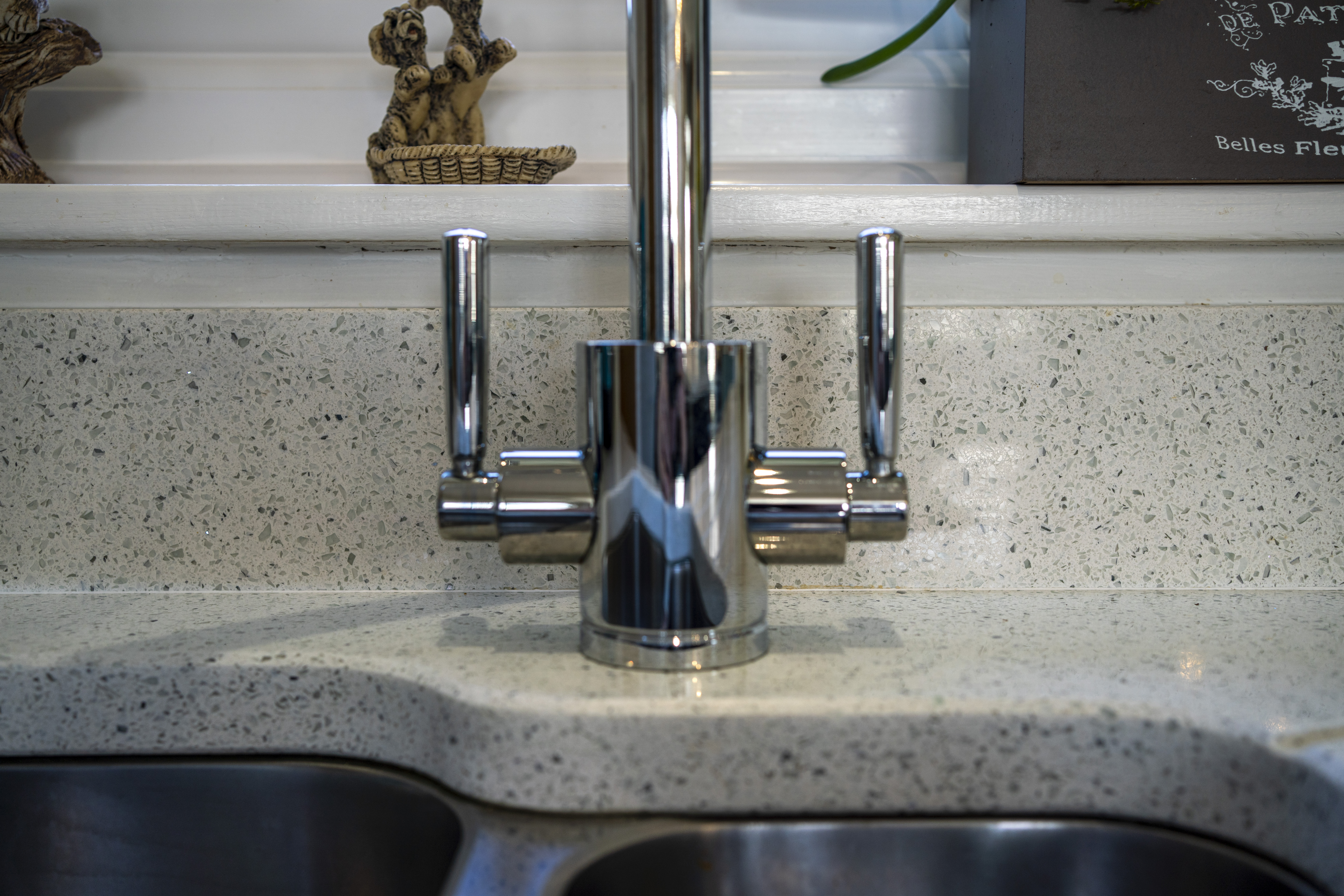 Chrome tap fitted on White Starlight Quartz worktops beside a stainless steel sink