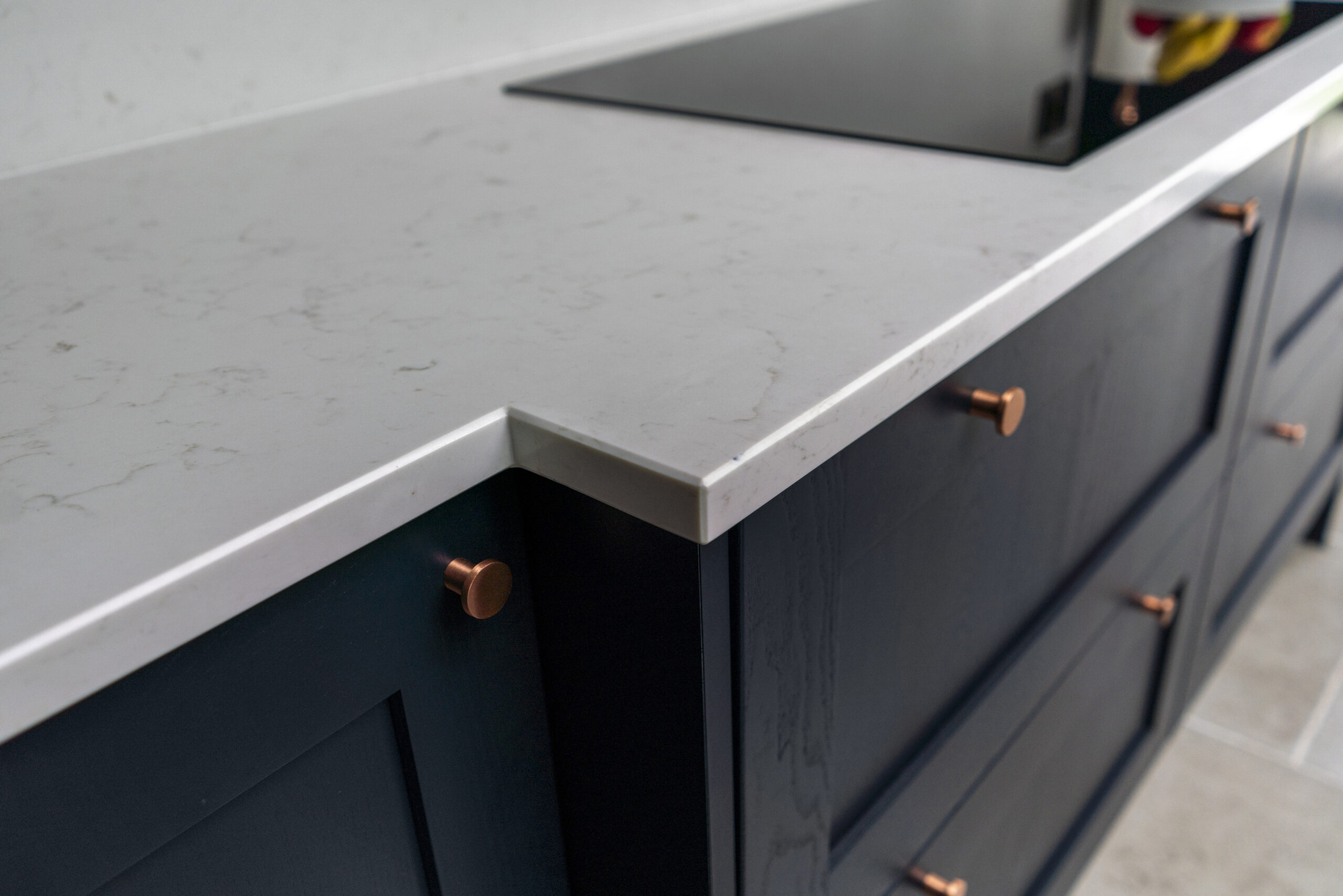 Carrara Quartz worktop on navy kitchen cabinets with copper handles