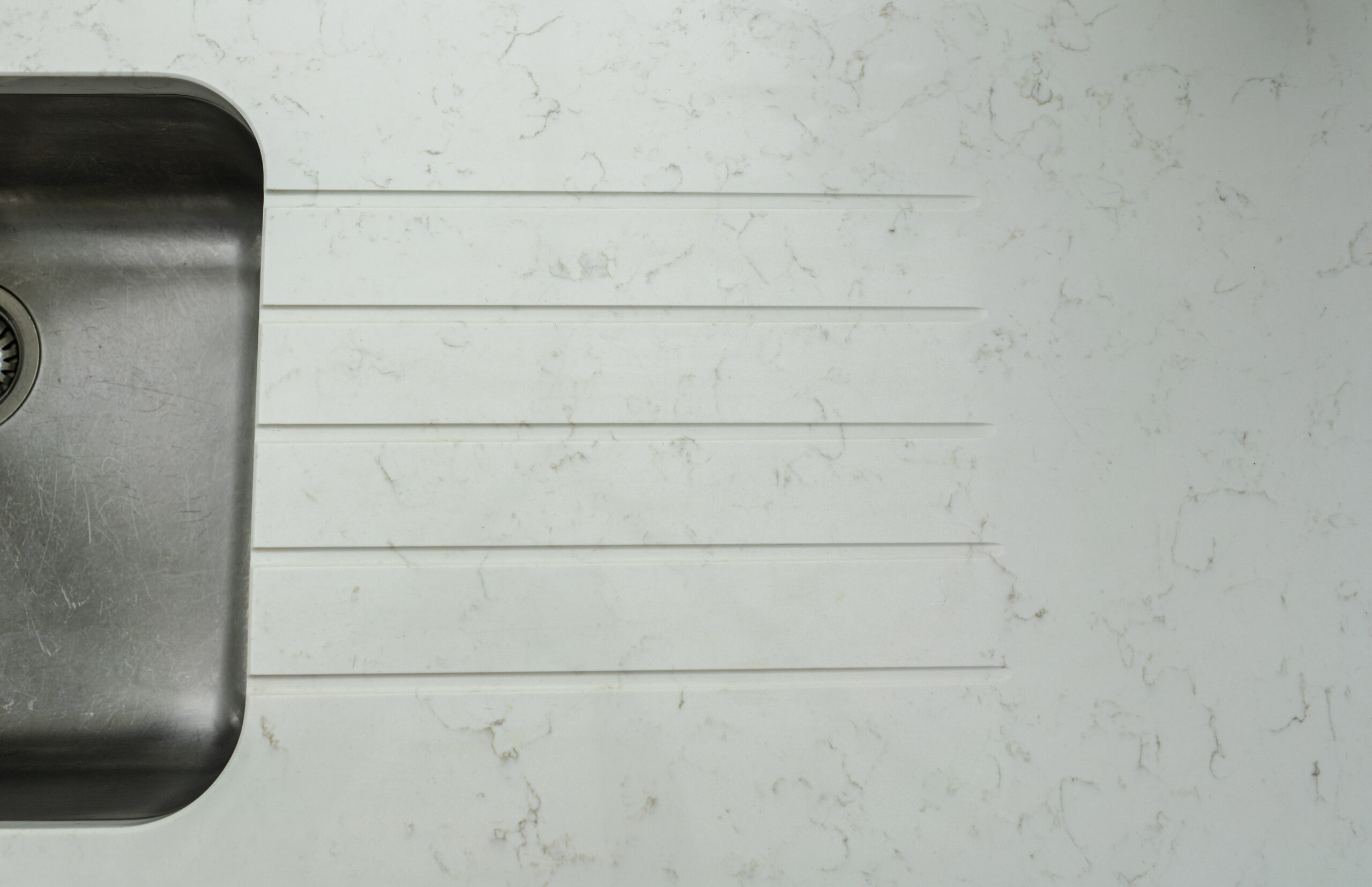 Carrara Quartz worktop with drainer grooves above a stainless steel sink