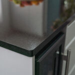 Close up of an Absolute Black Granite worktop corner with a polished edge, showing the end profile above a kitchen cupboard handle.