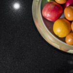 Corner detail of an Absolute Black Granite worktop with a fruit bowl, highlighting the smooth polished surface and deep black colour.