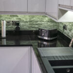 L shaped kitchen corner with Absolute Black Granite worktops and matching Granite upstand, showing the draining board and polished surface beside small appliances.