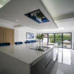 White Calacatta Quartz island in a contemporary kitchen with full height glazing and garden views