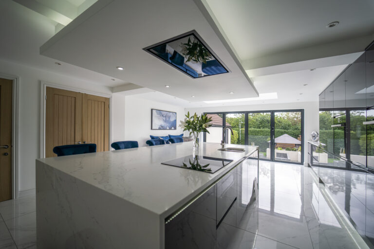 White Calacatta Quartz island in a contemporary kitchen with full height glazing and garden views