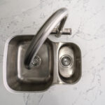 Close up of chrome tap fitted into White Calacatta Quartz worktop with grey veining