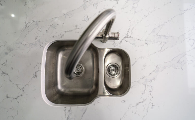 Close up of chrome tap fitted into White Calacatta Quartz worktop with grey veining