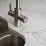 Chrome tap and double sink set into White Calacatta Quartz worktop with grey veining