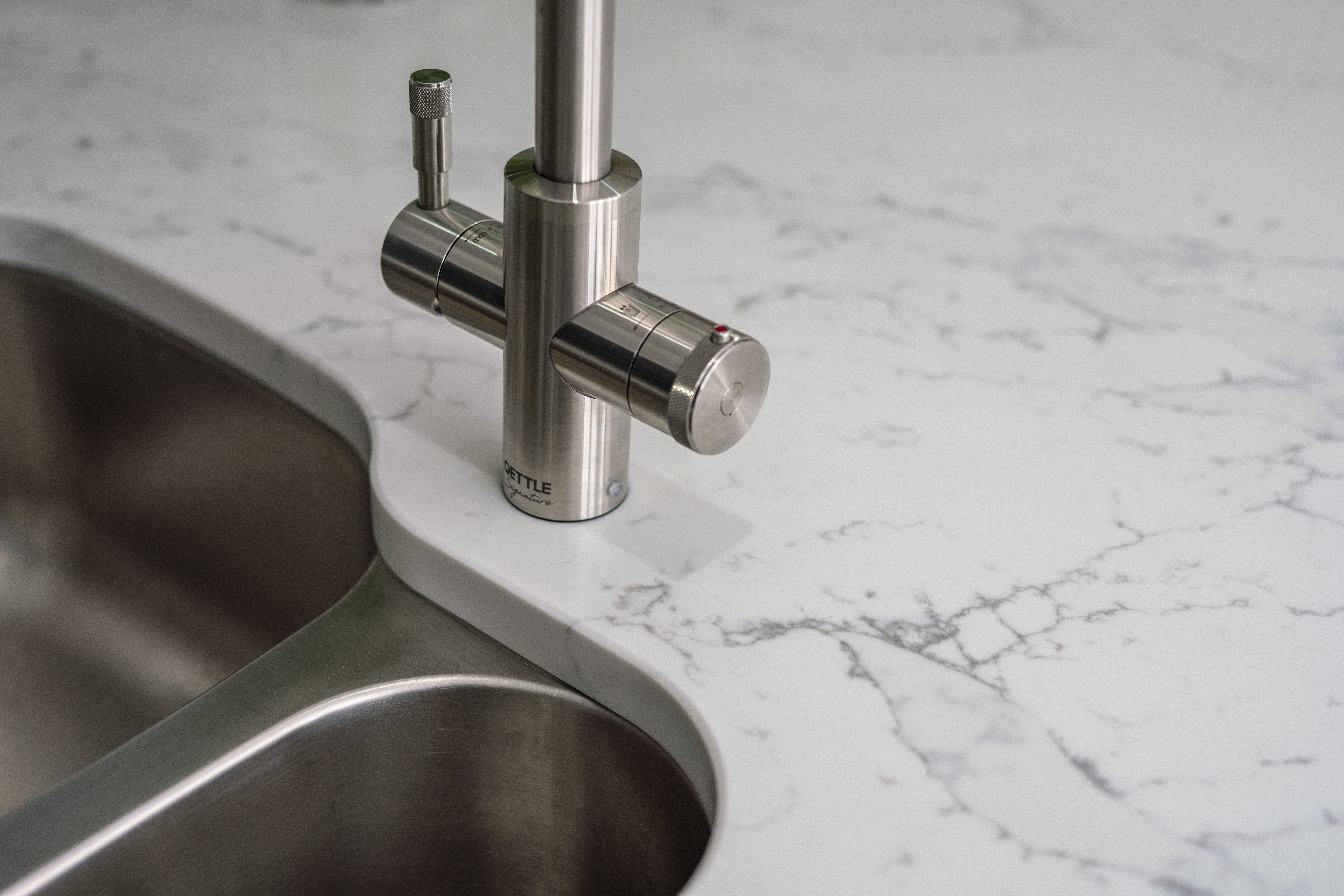 Chrome tap and double sink set into White Calacatta Quartz worktop with grey veining
