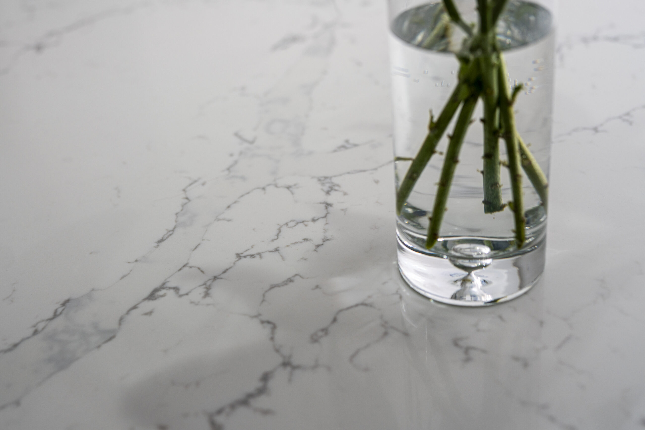 Close up of White Calacatta Quartz worktop surface with grey veining and vase of flowers