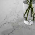 Close up of White Calacatta Quartz worktop surface with grey veining and vase of flowers