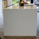 End view of an Olympus White Quartz kitchen island showing the smooth white finish and subtle veining