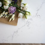 Olympus White Quartz worktop close-up with subtle grey veining beside flowers and kitchen styling