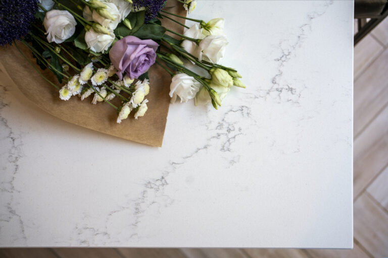 Olympus White Quartz worktop close-up with subtle grey veining beside flowers and kitchen styling