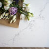 Olympus White Quartz worktop close-up with subtle grey veining beside flowers and kitchen styling