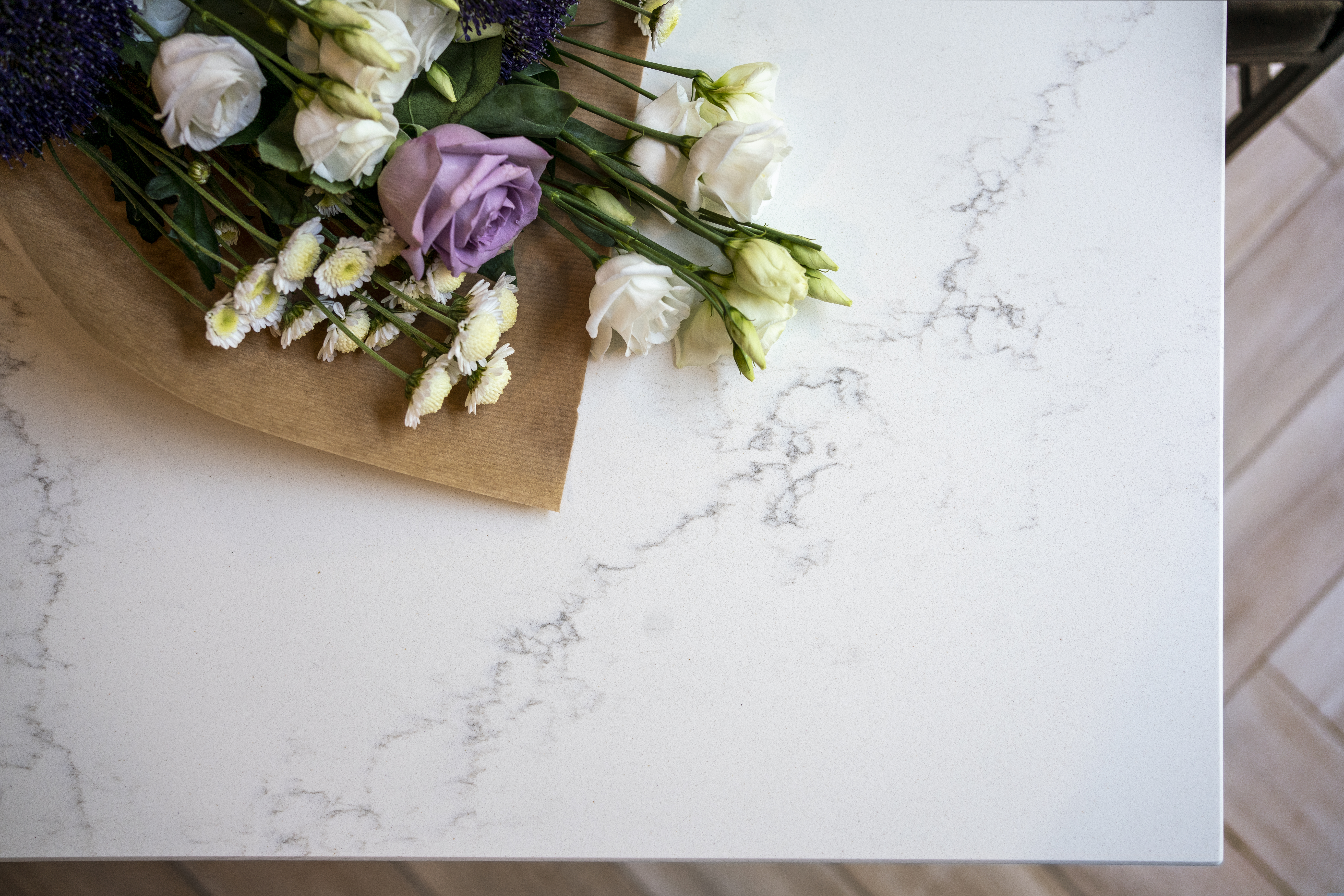 Olympus White Quartz worktop close-up with subtle grey veining beside flowers and kitchen styling