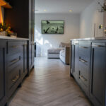 Long kitchen view with an Olympus White Quartz island worktop running through the centre of dark cabinetry