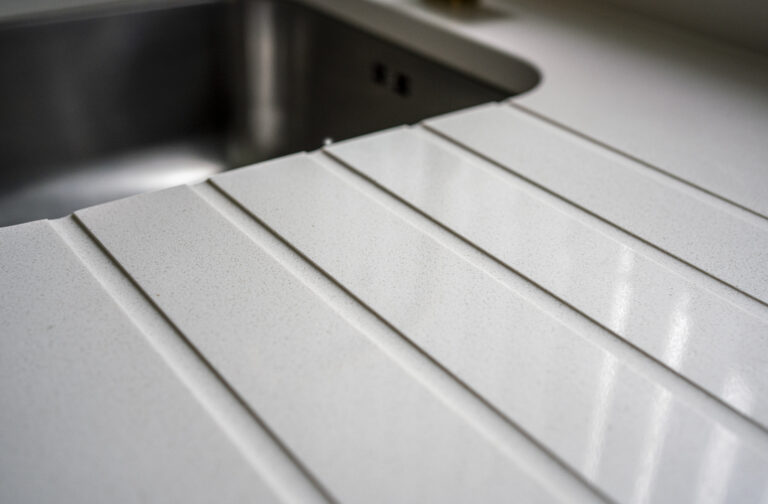 Close-up of Imperial White Quartz drainer grooves beside an inset sink with clean, straight channels