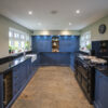Full room view of a blue kitchen with Absolute Black Granite worktops, showing the main worktop runs, appliances and open floor space.