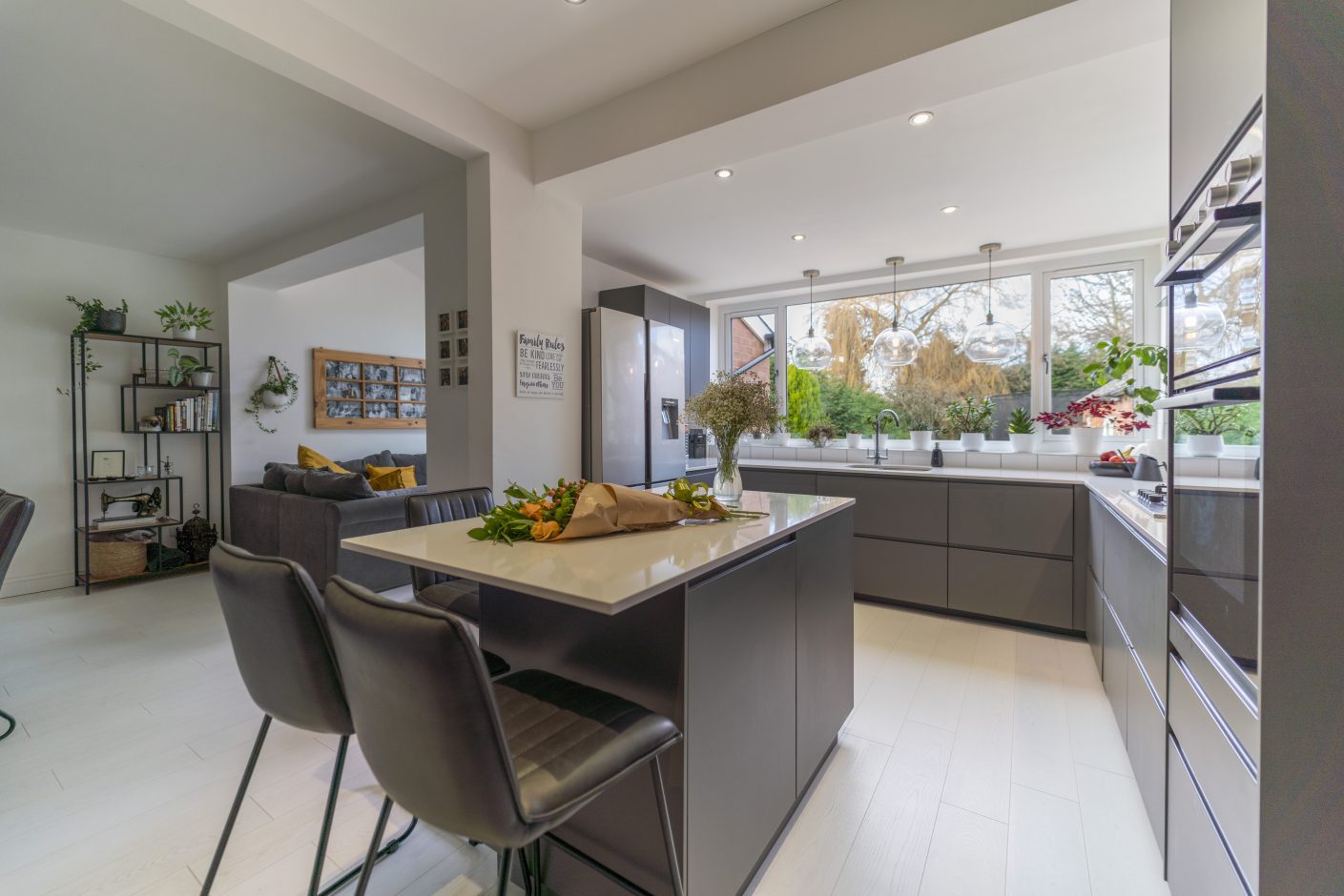 Open-plan kitchen with Blanco Zeus Quartz island worktop and bright white surface with seating in front of large windows