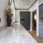 Perspective view along an Ivory Fantasy Granite worktop run showing the Granite pattern and polished edge, with flowers and a plant at the far end.