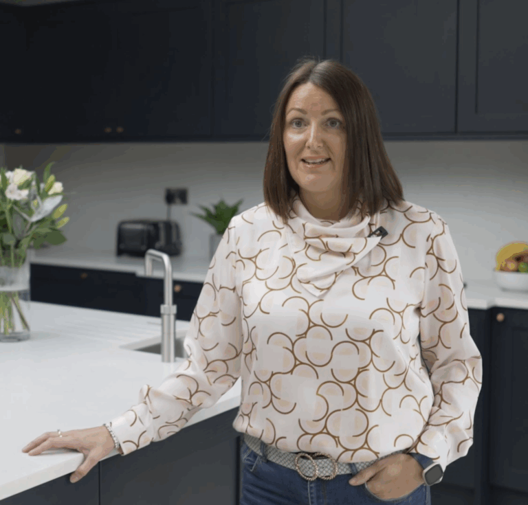 Customer standing in her kitchen with Carrara Quartz worktops installed by Mayfair Worktops